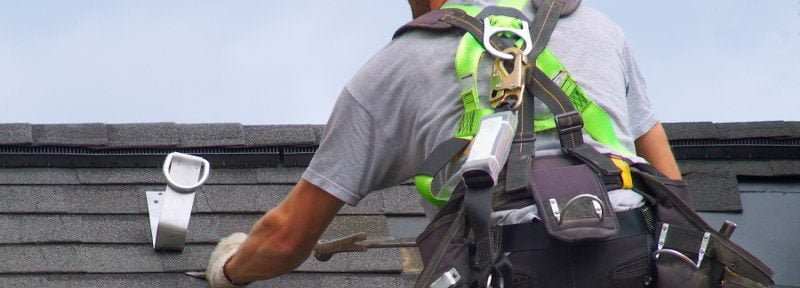 man on roof using safety equipment